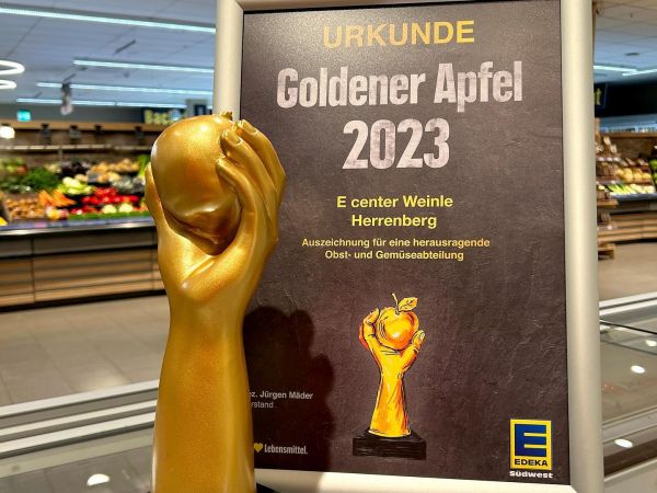 Plakat zum Gewinn des Goldenen Apfels durch das e-Center Weinle, Herrenberg mit dem "Pokal" des goldenen Apfels gehalten einer goldenen Hand