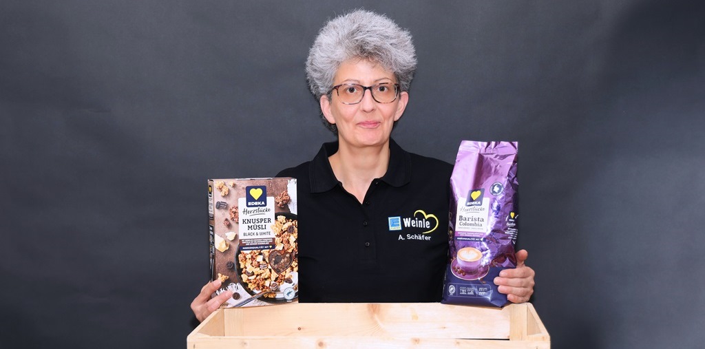 Mitarbeiterin im Edeka T-Shirt mit einer Müsli- und einer Kaffepackung im Vordergrund
